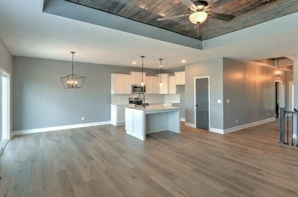 kitchen with stainless steel microwave, baseboards, open floor plan, and a kitchen island with sink