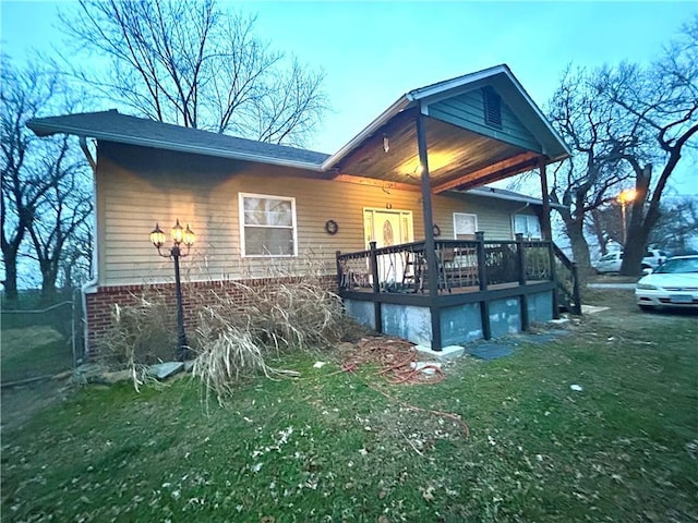 back of property featuring a wooden deck and a lawn