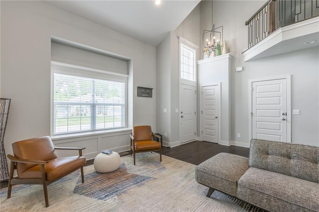 sitting room featuring wood-type flooring, a towering ceiling, and a notable chandelier