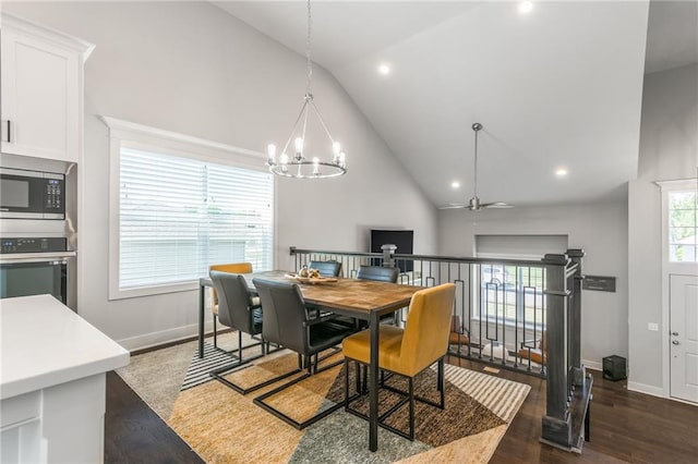 dining area with ceiling fan with notable chandelier, dark hardwood / wood-style floors, and high vaulted ceiling