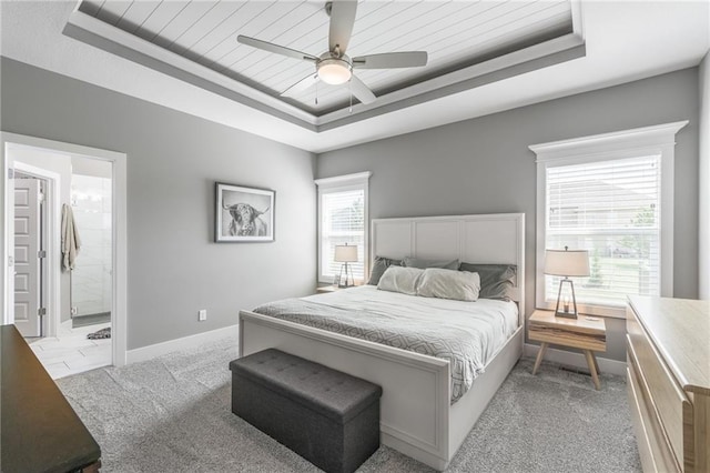 carpeted bedroom featuring connected bathroom, a tray ceiling, and ceiling fan