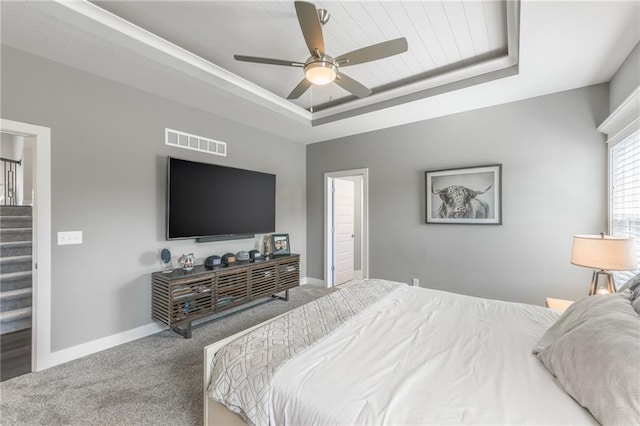 carpeted bedroom with a tray ceiling and ceiling fan