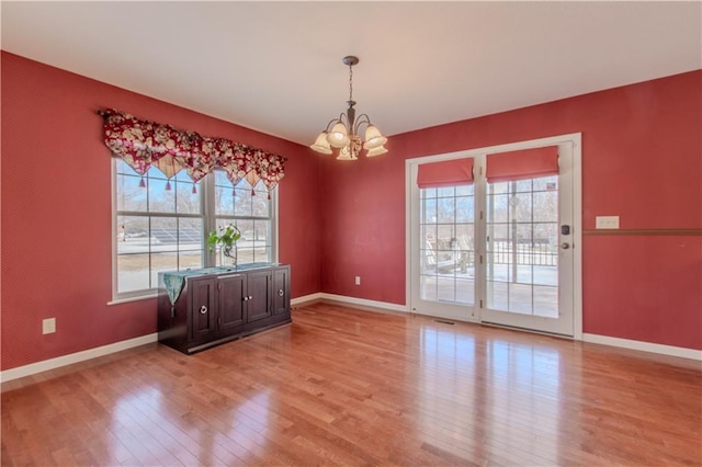 unfurnished dining area with an inviting chandelier, light hardwood / wood-style floors, and plenty of natural light