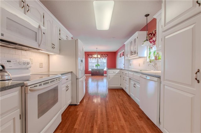 kitchen featuring white cabinetry, decorative backsplash, decorative light fixtures, and white appliances