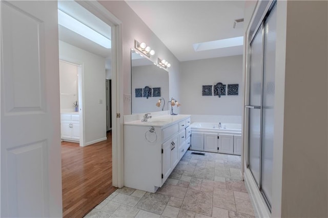 bathroom featuring vanity, a skylight, and separate shower and tub