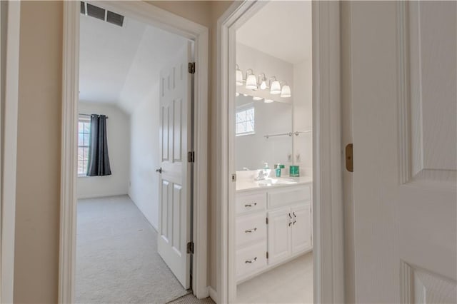 hallway with light colored carpet and sink