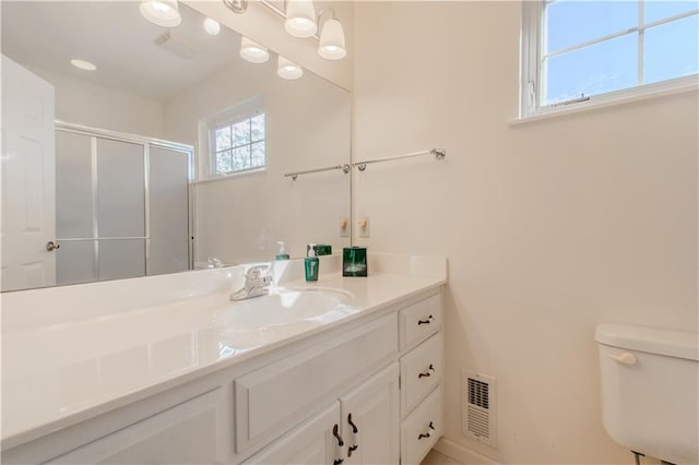 bathroom featuring toilet, a shower with door, and vanity