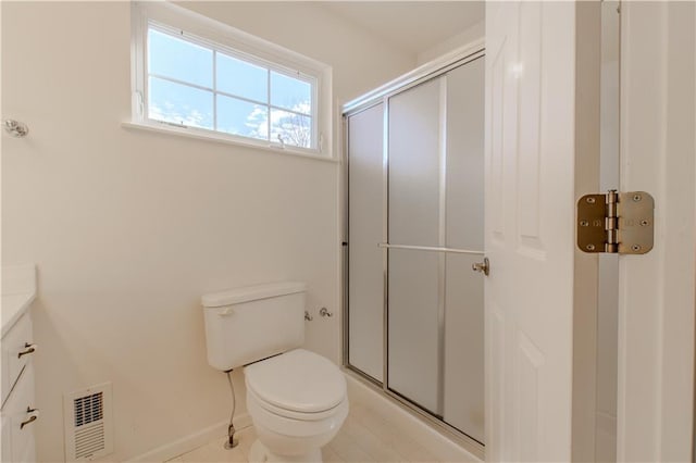 bathroom featuring toilet, a shower with shower door, and vanity