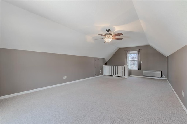 additional living space featuring ceiling fan, light colored carpet, vaulted ceiling, and a wall mounted air conditioner