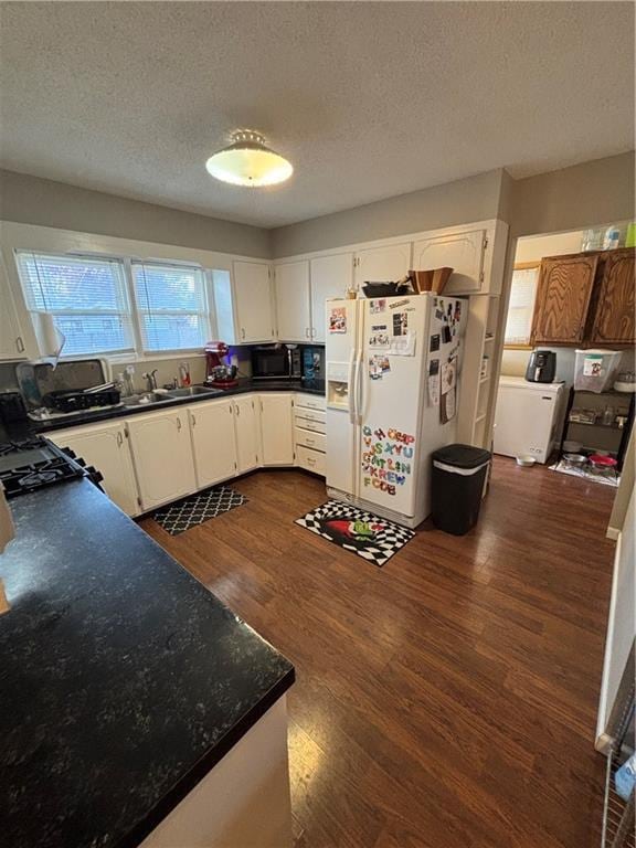 kitchen featuring white cabinetry, white fridge with ice dispenser, sink, dark wood-type flooring, and a textured ceiling