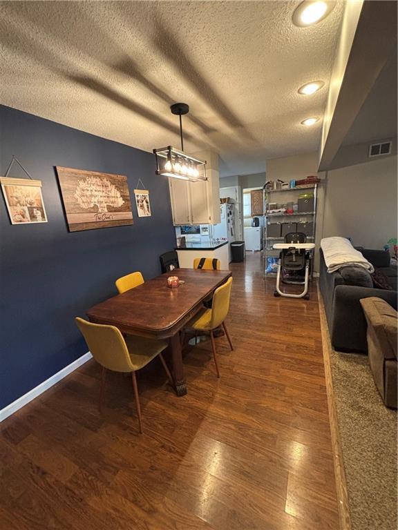 dining room featuring a textured ceiling, dark hardwood / wood-style floors, and lofted ceiling