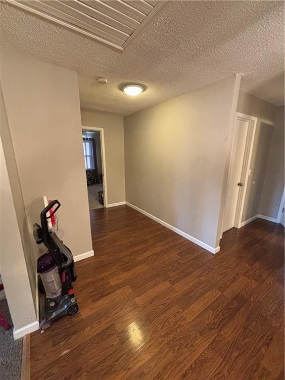 unfurnished room featuring a textured ceiling and dark hardwood / wood-style floors