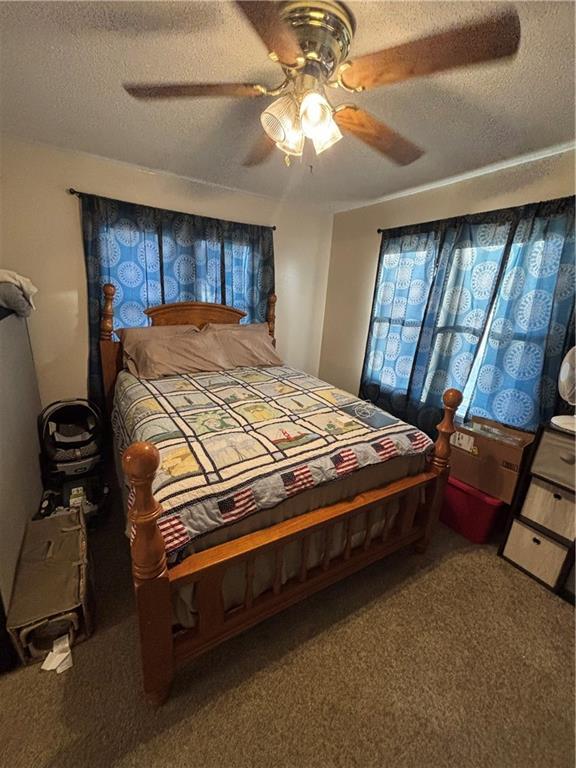 bedroom with carpet flooring, ceiling fan, and a textured ceiling