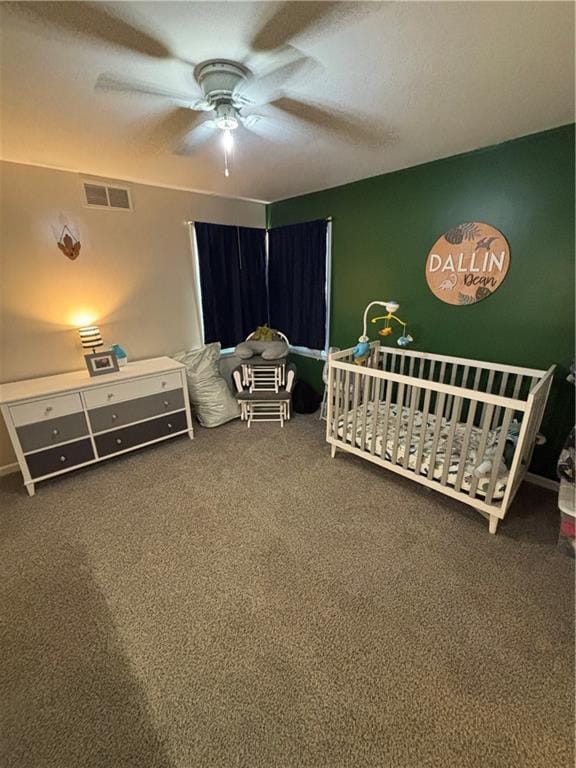 carpeted bedroom featuring ceiling fan and a nursery area