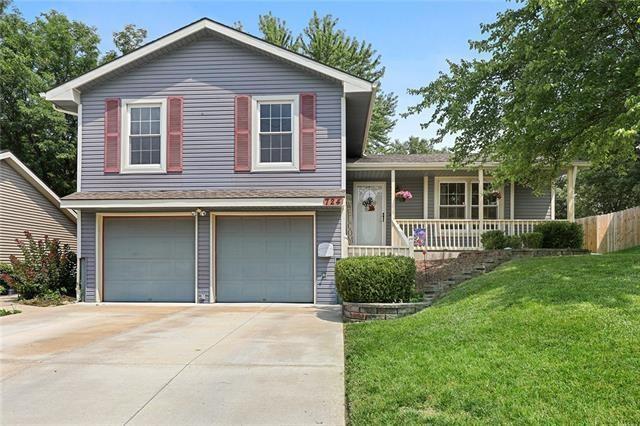 split level home featuring covered porch, a front yard, and a garage