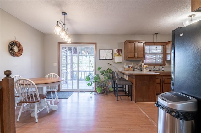 kitchen featuring light hardwood / wood-style flooring, kitchen peninsula, pendant lighting, a textured ceiling, and a breakfast bar