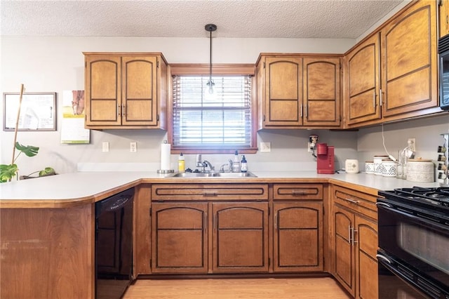 kitchen featuring black appliances, sink, decorative light fixtures, light hardwood / wood-style floors, and kitchen peninsula