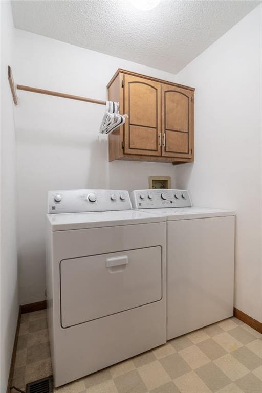 laundry area with cabinets, a textured ceiling, and washing machine and clothes dryer