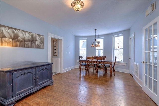 dining space with hardwood / wood-style floors and a chandelier