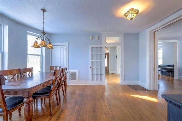 dining room with hardwood / wood-style flooring, french doors, and a chandelier