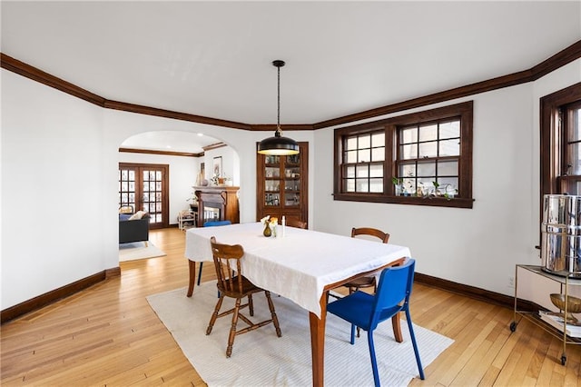 dining space with ornamental molding, french doors, and light wood-type flooring