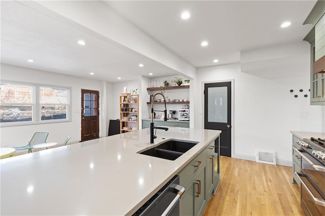 kitchen featuring sink, light hardwood / wood-style flooring, stainless steel appliances, and green cabinetry