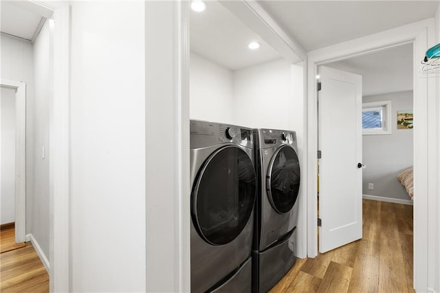 laundry area with separate washer and dryer and light wood-type flooring