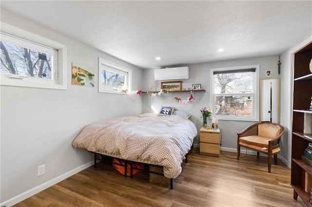 bedroom featuring dark wood-type flooring, multiple windows, and a wall unit AC