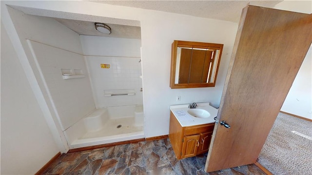 bathroom with vanity, a shower, and a textured ceiling