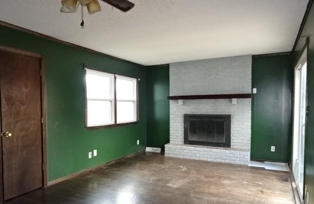 unfurnished living room featuring a textured ceiling, ceiling fan, wood-type flooring, and a fireplace