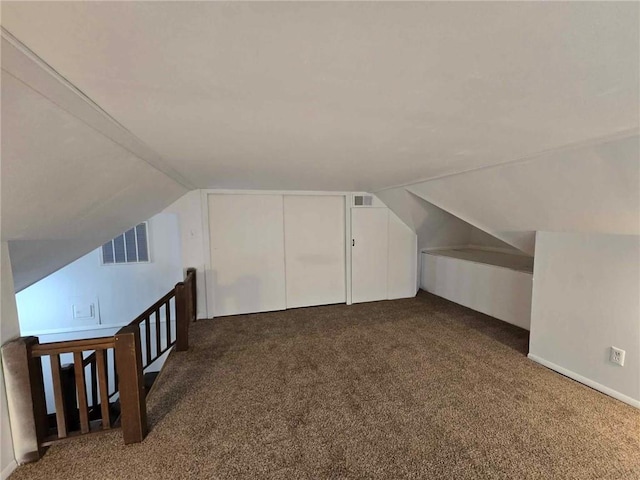 bonus room with lofted ceiling and dark colored carpet