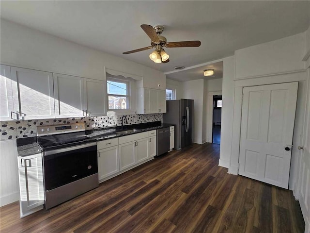 kitchen featuring backsplash, dark wood-type flooring, white cabinets, sink, and appliances with stainless steel finishes