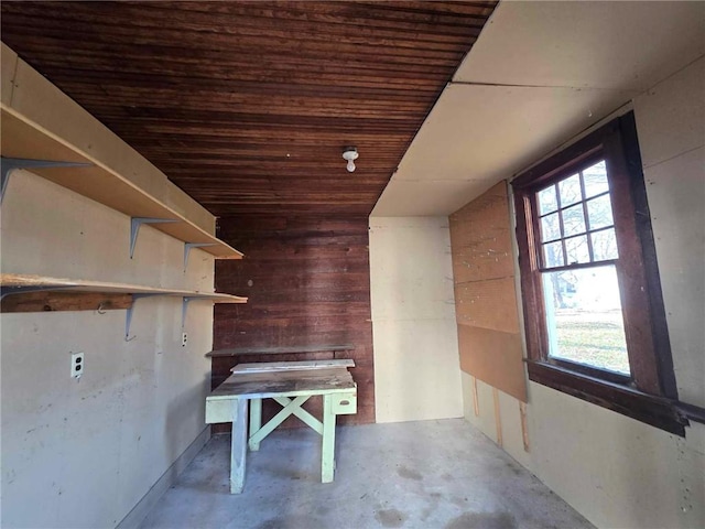 interior space featuring concrete flooring, wooden walls, and wood ceiling