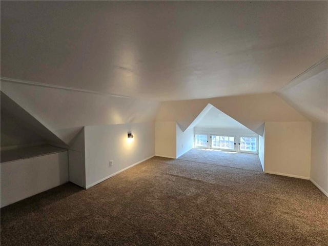 additional living space featuring dark carpet and lofted ceiling