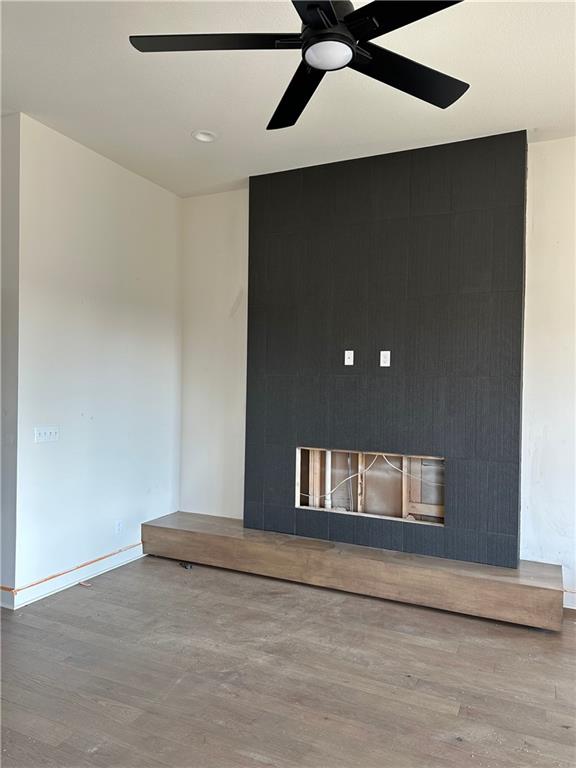 spare room featuring hardwood / wood-style floors, ceiling fan, and a tile fireplace