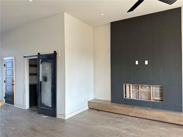 interior space with hardwood / wood-style floors, ceiling fan, and a barn door