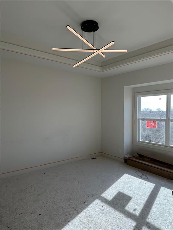 carpeted spare room featuring a notable chandelier