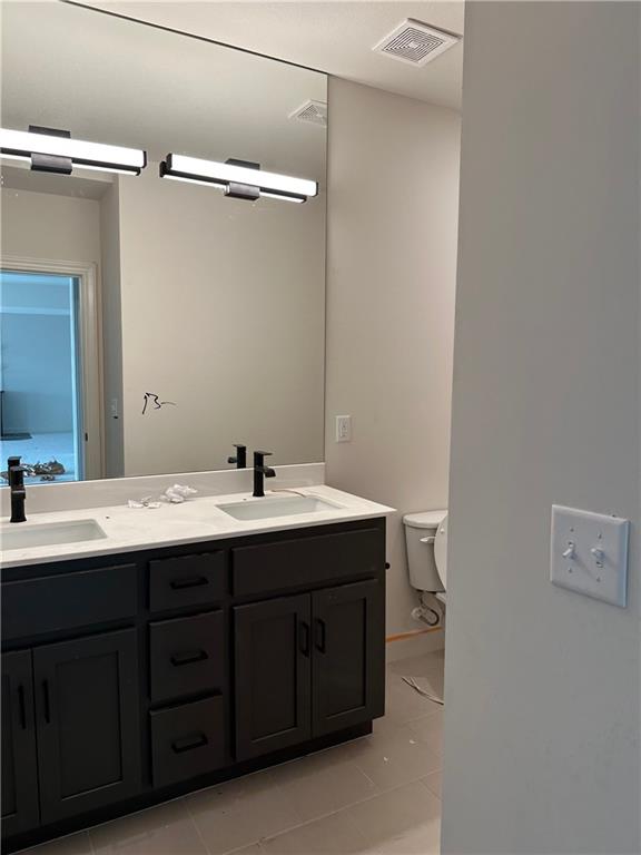 bathroom with toilet, vanity, and tile patterned floors