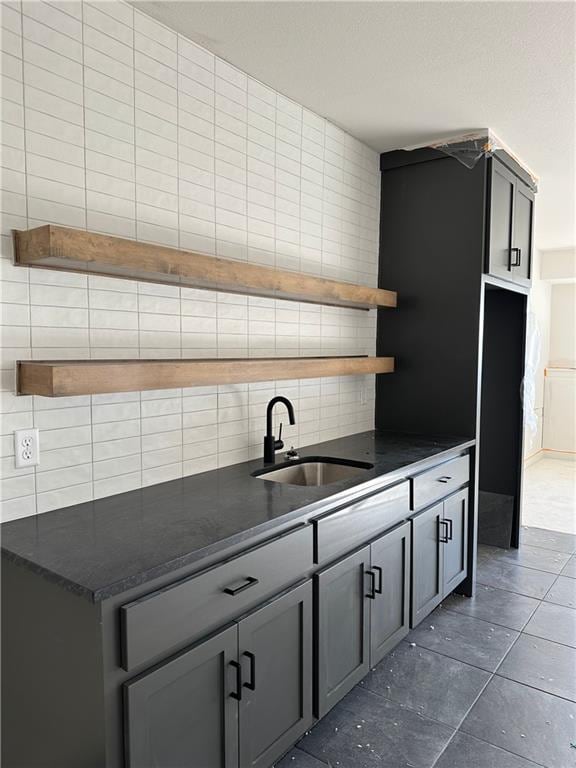 kitchen featuring backsplash, gray cabinets, tile walls, and sink