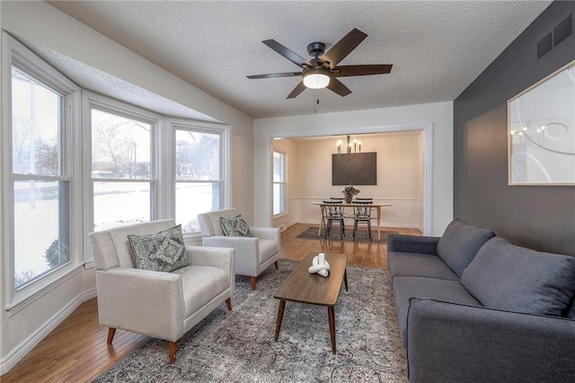 living room with hardwood / wood-style floors, ceiling fan, and a textured ceiling