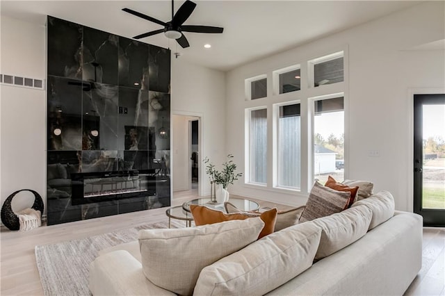 living room with a fireplace, ceiling fan, and light hardwood / wood-style flooring