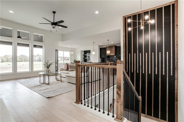 living room featuring ceiling fan with notable chandelier and light wood-type flooring