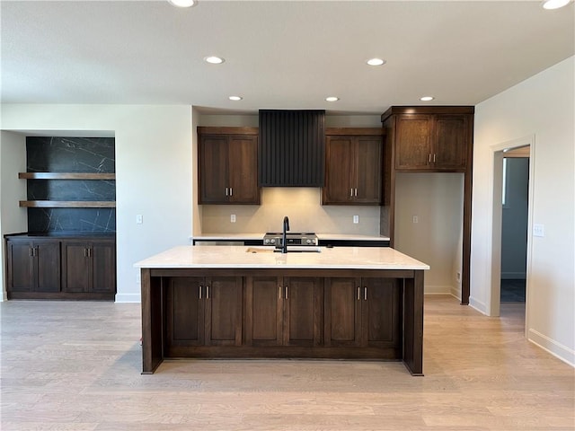 kitchen featuring dark brown cabinetry, light countertops, a sink, and light wood finished floors