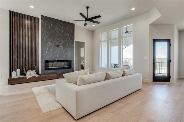 living area with recessed lighting, wood finished floors, ceiling fan, and a fireplace