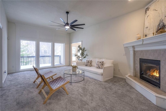 unfurnished living room with carpet, ceiling fan, and a tiled fireplace