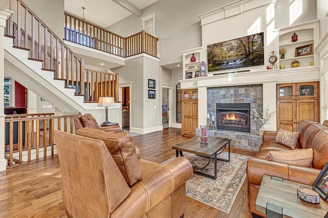 living room with a fireplace, hardwood / wood-style floors, and a towering ceiling