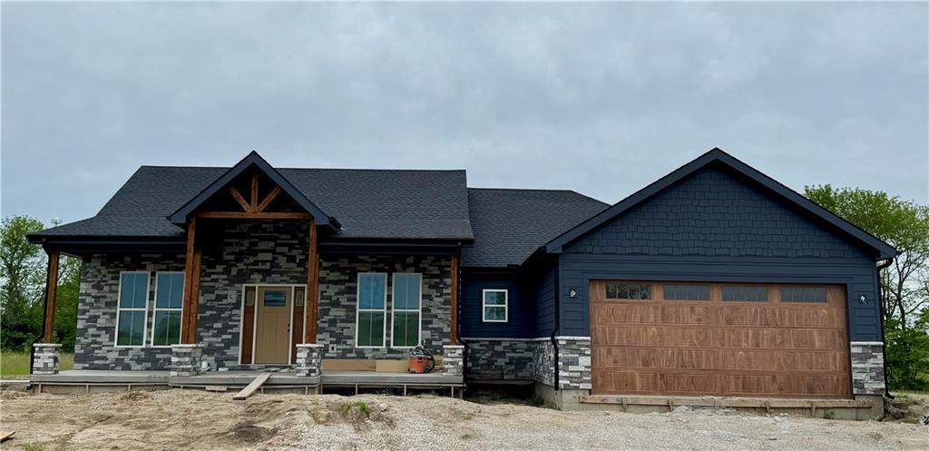 12749 NE Seminole Rd, Adrian, MO 64720 - view of front facade featuring covered porch, stone siding, and an attached garage