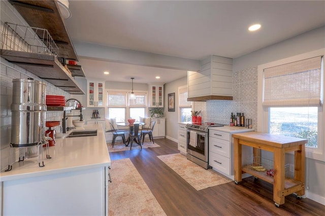 kitchen featuring premium range hood, dark wood-type flooring, sink, electric stove, and hanging light fixtures