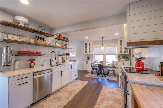 kitchen with sink, stainless steel appliances, wooden counters, pendant lighting, and white cabinets