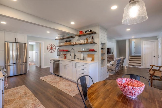 interior space featuring sink, stainless steel appliances, dark hardwood / wood-style floors, pendant lighting, and white cabinets